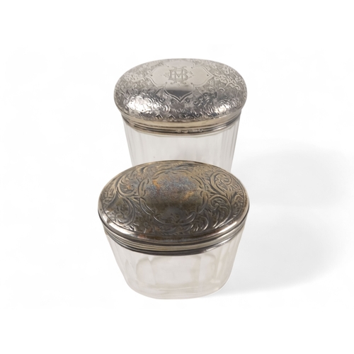 500 - Two silver mounted glass bottles - London 1893, oval with a faceted body, the domed top with foliate... 