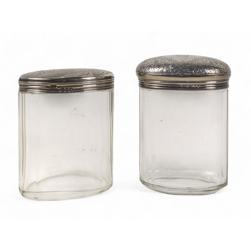 500 - Two silver mounted glass bottles - London 1893, oval with a faceted body, the domed top with foliate... 