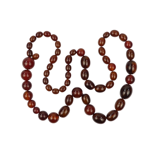 616 - A string of graduated oval cherry 'amber' beads - length 80cm.