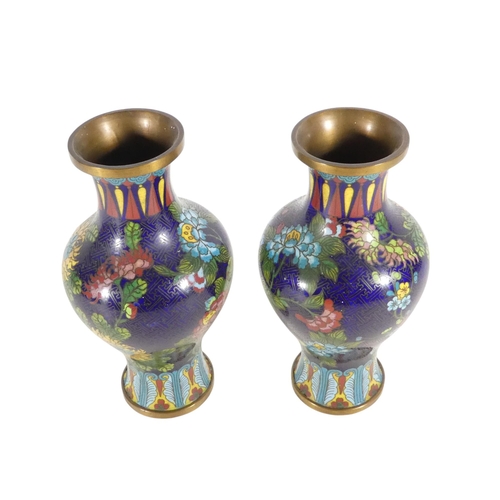 334 - A pair of early 20th century cloisonne vases - of baluster form, decorated with flowers on a blue gr... 