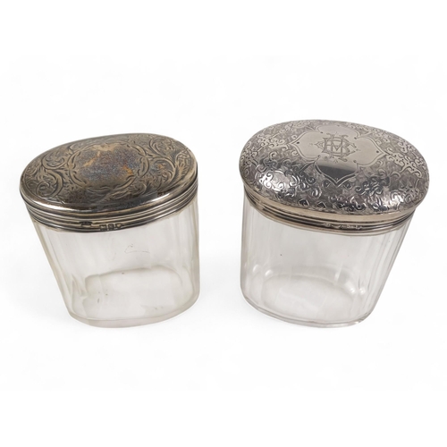 500 - Two silver mounted glass bottles - London 1893, oval with a faceted body, the domed top with foliate... 