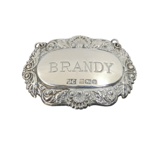 507 - A silver bottle label - Birmingham 1985, engraved 'Brandy' within a foliate band, together with six ... 