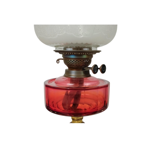 51 - A late 19th century oil lamp - with ruby glass reservoir and fluted baluster support and circular ba... 