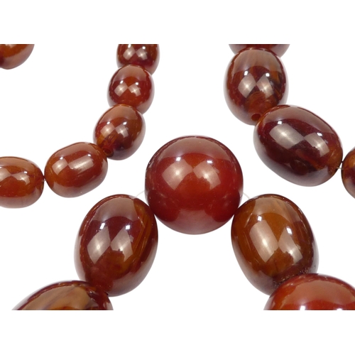 616 - A string of graduated oval cherry 'amber' beads - length 80cm.