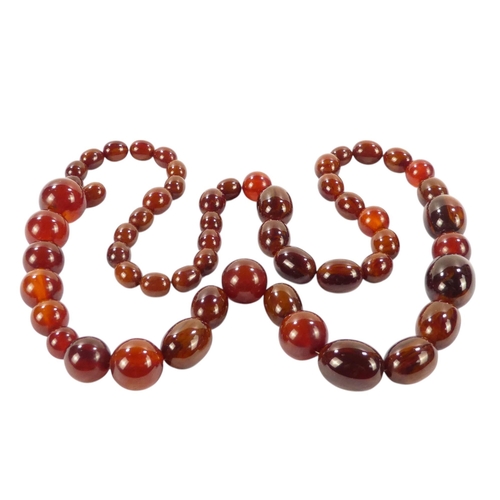 616 - A string of graduated oval cherry 'amber' beads - length 80cm.