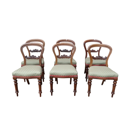 914 - A set of six Victorian walnut dining chairs - with balloon backs and overstuffed seats, on turned ta... 