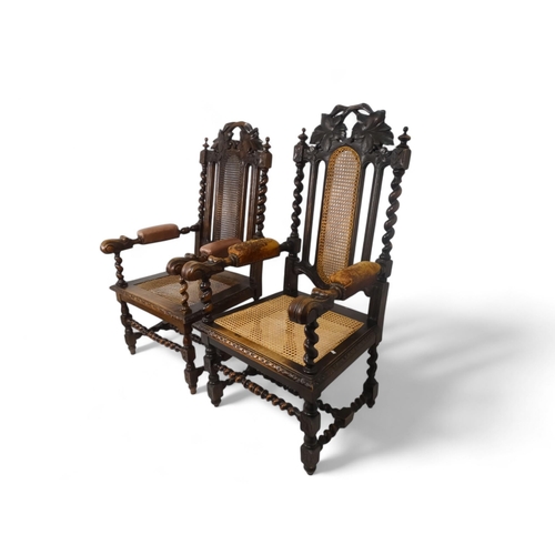 923 - A pair of 17th century style oak open arm chairs - with cane backs flanked by spiral turned supports... 