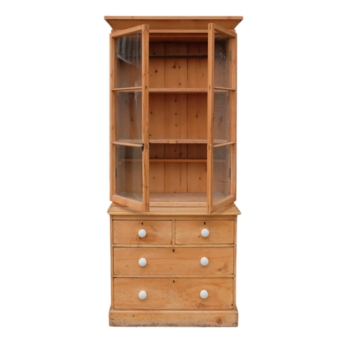 924 - A 19th century pine bookcase chest - the upper section with cornice above a pair of glazed panel doo... 