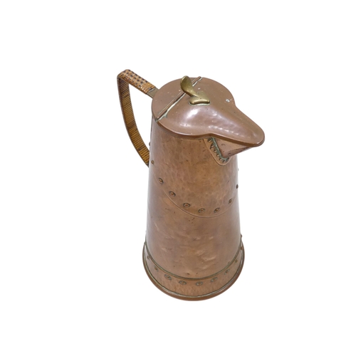 99 - A WMF Arts and Crafts copper hot water jug - with wicker handle and a riveted design, marked to base... 