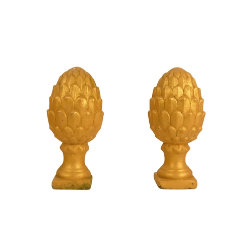 110 - A pair of cast stone finials - modelled in the form of pineapples and gilt decorated, 31cm high (2)