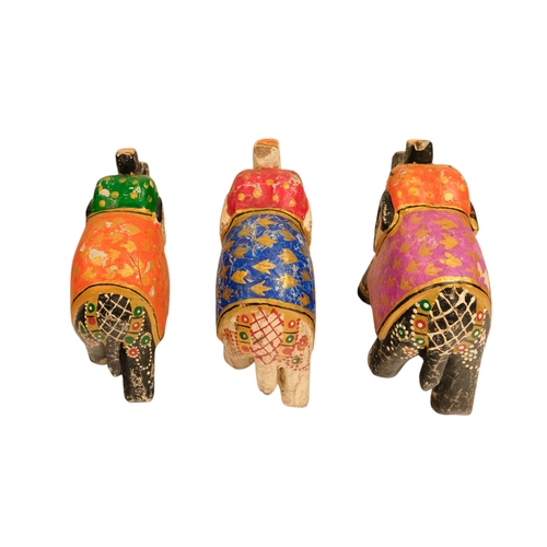 111 - Three polychrome painted elephants - one white and two black, with coloured blankets featuring gilt ... 