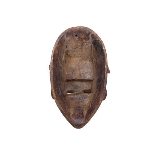 69 - A carved hardwood African mask - polychrome painted with a white face and terracotta flashes, 30cm h... 