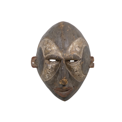 70 - A carved hardwood African mask - dark stained and decorated with white disks, 28cm high