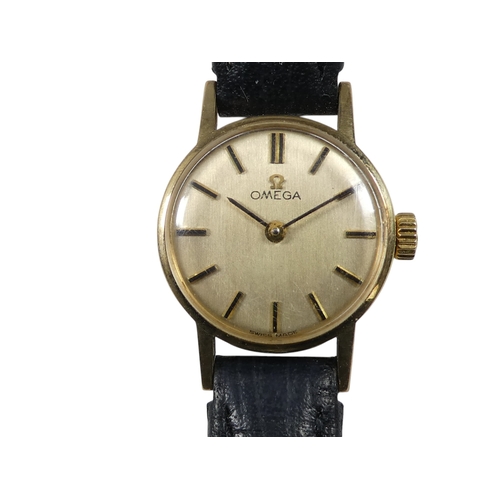 703 - A 9ct ladies Omega wristwatch - the gilt dial set out with batons, on a black leather strap with bra... 