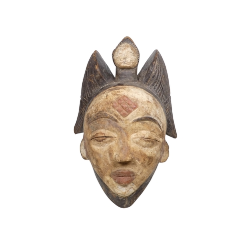 71 - A carved wooden and polychrome painted African mask - with winged headdress and figure, the white fa... 