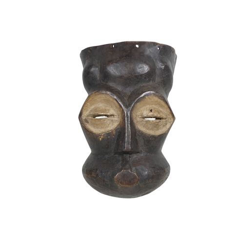 72 - A carved hardwood African mask - dark stained with whie eye sockets, 22cm high