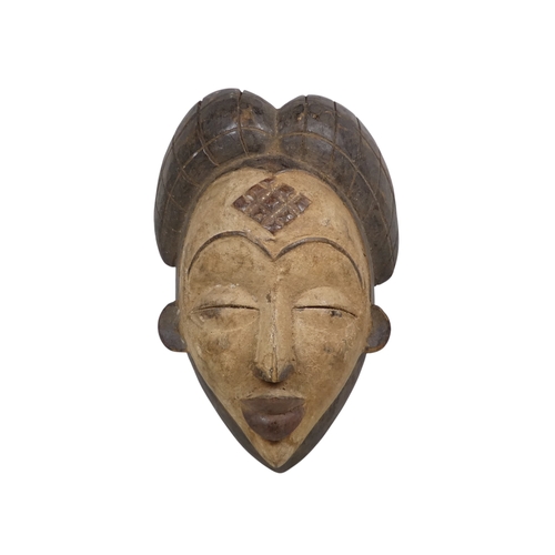 74 - A carved hardwood African mask - with an accentuated hair arrangment and white face, 31cm high