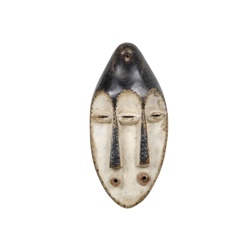 75 - A carved hardwood African mask - elongated with three eyes, two noses and mouths, the faces with a w... 