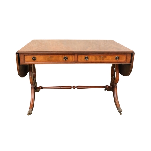 931 - A George III sytle mahogany sofa table - the rectangular top with drop ends, on lyre shaped end supp... 