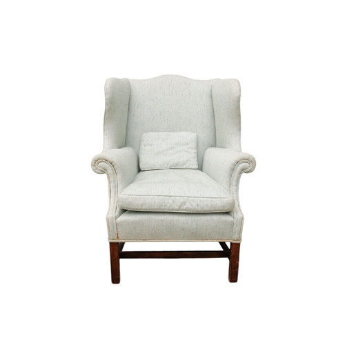 939 - A George III style mahogany wing armchair - light blue upholstery with a loose cushion seat, on squa... 