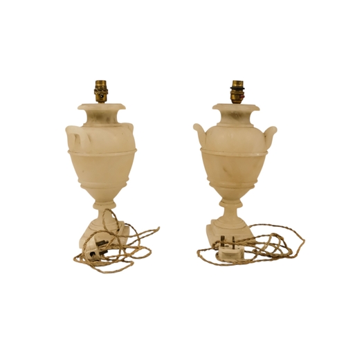 16 - A pair of early 20th century alabaster table lamps - of urn form with twin handles and raised on a s... 