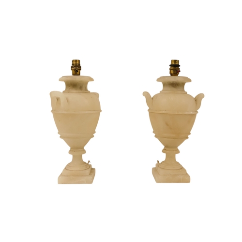 16 - A pair of early 20th century alabaster table lamps - of urn form with twin handles and raised on a s... 