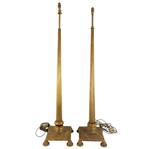 18 - A pair of brass adjustable standard lamps - with reeded columns and square bases on bun feet. (2)
