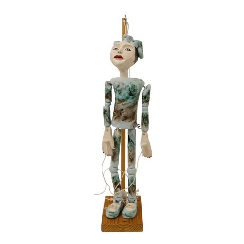 23 - A contemporary ceramic dancing doll - with horned head and articulated limbs, with a soft wood stand... 
