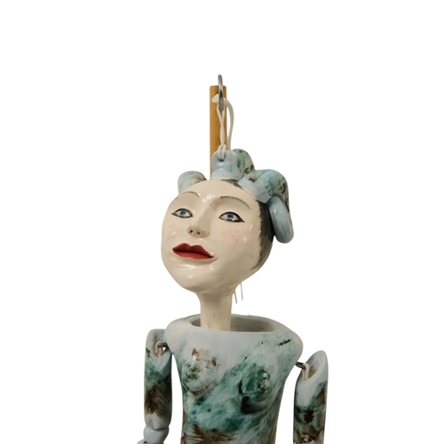 23 - A contemporary ceramic dancing doll - with horned head and articulated limbs, with a soft wood stand... 