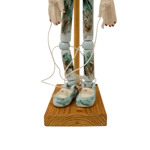 23 - A contemporary ceramic dancing doll - with horned head and articulated limbs, with a soft wood stand... 
