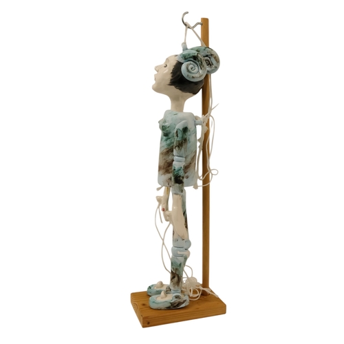23 - A contemporary ceramic dancing doll - with horned head and articulated limbs, with a soft wood stand... 