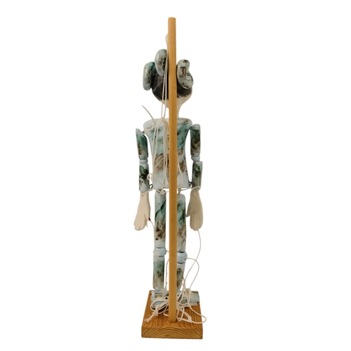 23 - A contemporary ceramic dancing doll - with horned head and articulated limbs, with a soft wood stand... 