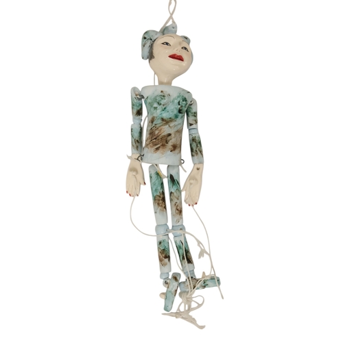 23 - A contemporary ceramic dancing doll - with horned head and articulated limbs, with a soft wood stand... 