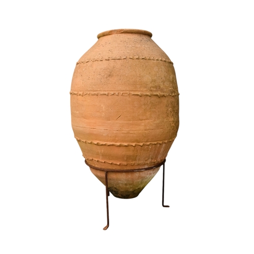 36 - A vintage terracotta olive jar - of classical form with a ribbed girdle, on a steel stand 53 x 90cm.