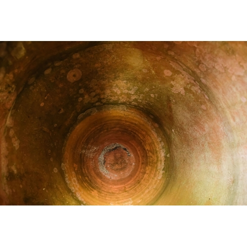 36 - A vintage terracotta olive jar - of classical form with a ribbed girdle, on a steel stand 53 x 90cm.