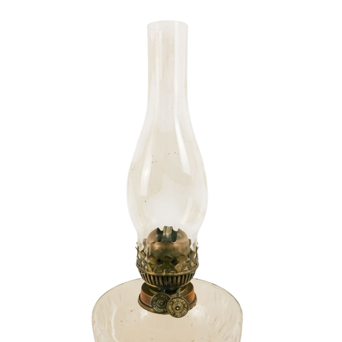 40 - A late Victorian oil lamp - with a flash-cut clear glass reservoir on a repousse brass support and c... 