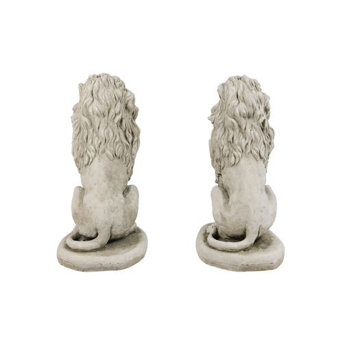 58 - A pair of reconstituted stone lions - in a seated pose, 40cm high. (2)
