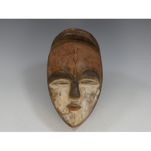117 - An African hardwood mask - with a red forehead and white cheeks and jaw, 27cm high.