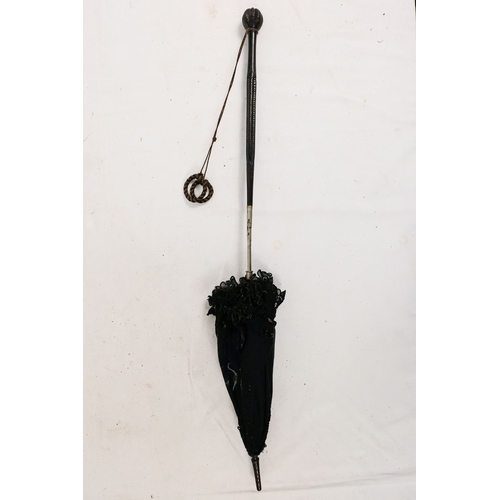 141 - An early 20th century parasol - with an oriental white metal handle profusely decorated with foliage... 