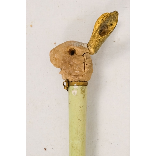 142 - An early 20th century white silk parasol - the green painted handle terminating in a carved rabbits ... 
