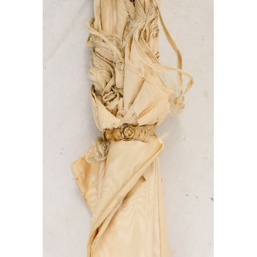 142 - An early 20th century white silk parasol - the green painted handle terminating in a carved rabbits ... 