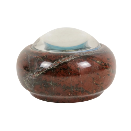 128 - A red serpentine souvenir paperweight - of circular form and decorated with an image of Cadgwith, 12... 