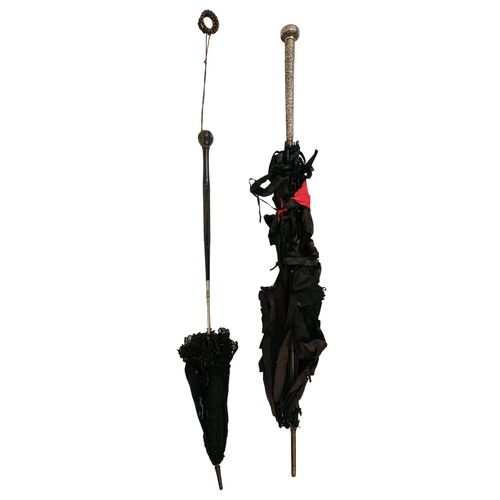 141 - An early 20th century parasol - with an oriental white metal handle profusely decorated with foliage... 