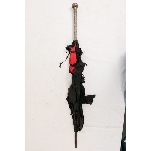 141 - An early 20th century parasol - with an oriental white metal handle profusely decorated with foliage... 