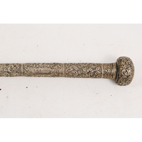 141 - An early 20th century parasol - with an oriental white metal handle profusely decorated with foliage... 