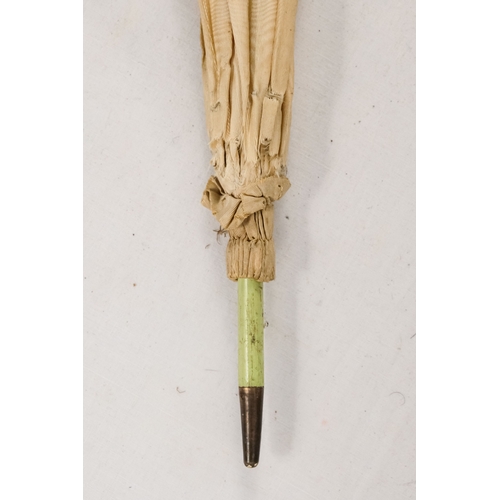142 - An early 20th century white silk parasol - the green painted handle terminating in a carved rabbits ... 
