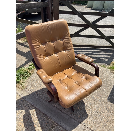 115 - 1970s swivel armchair with tan vinyl upholstery, wooden frame, and padded armrests.