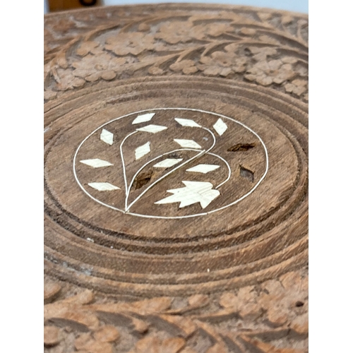 4 - Hand-carved wooden table featuring intricate floral designs and inlay on the top surface. Sturdy, de... 