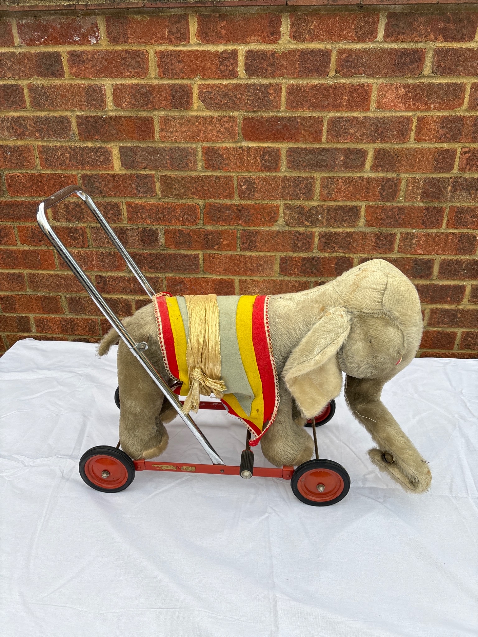 Merrythought wheeled toy elephant with red frame and yellow-striped saddle.