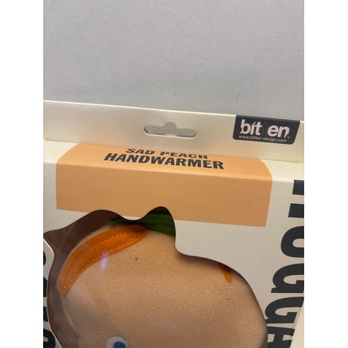 118 - Bitten Sad Peach Handwarmer in original packaging.
